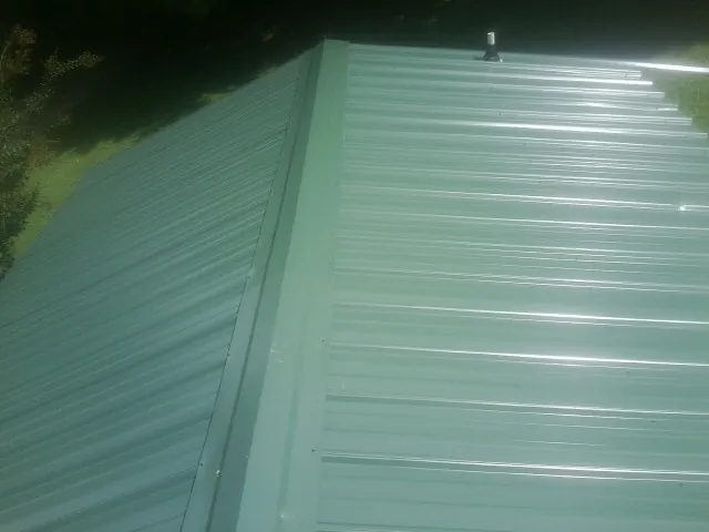 New green metal panels meeting at the ridge of a roof — Flat Roof Repair work by our crew in Murray