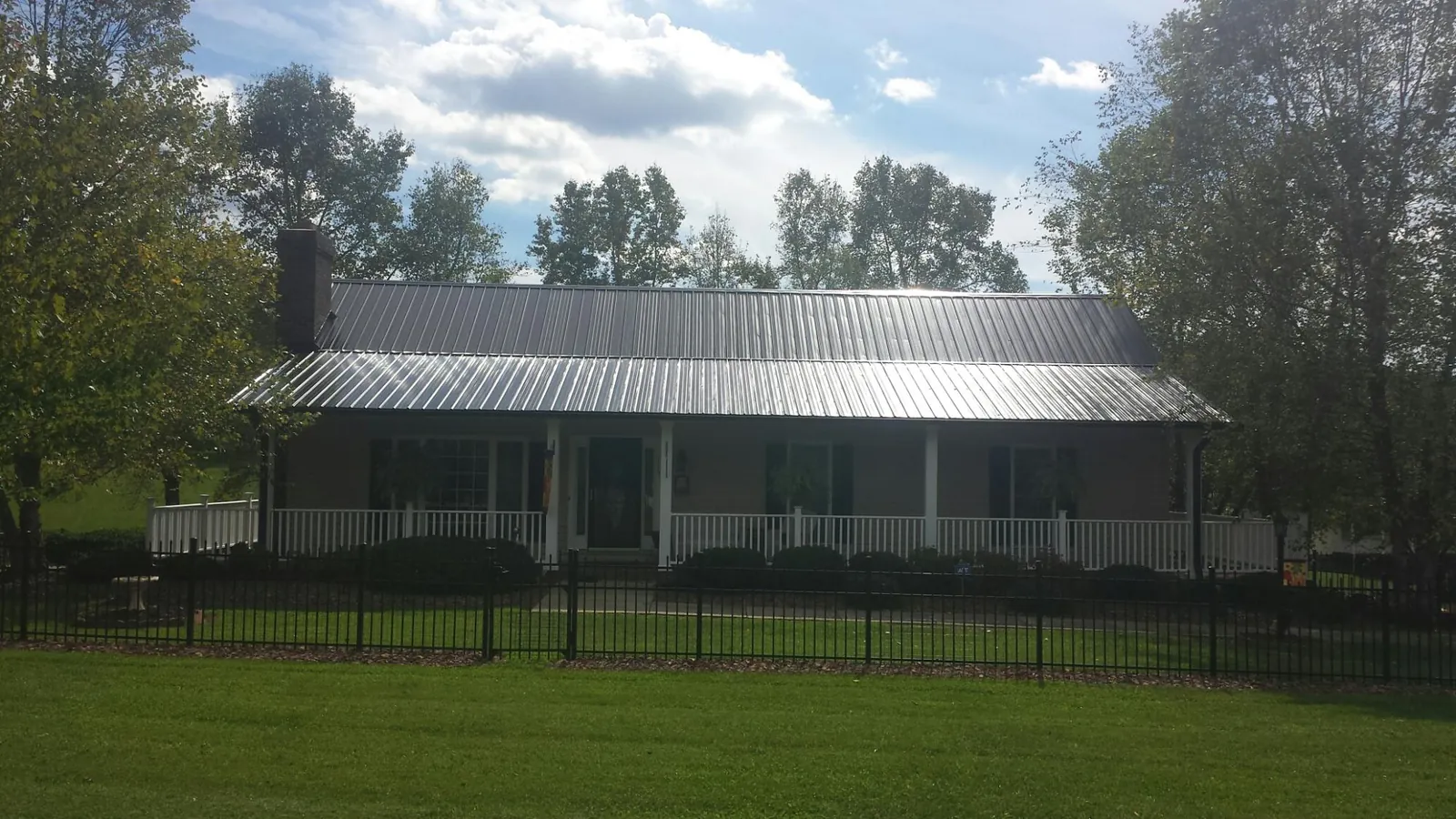 Gray metal roof on a brick ranch with a full width front porch — Gutter Guard Installation work by our crew in Murray
